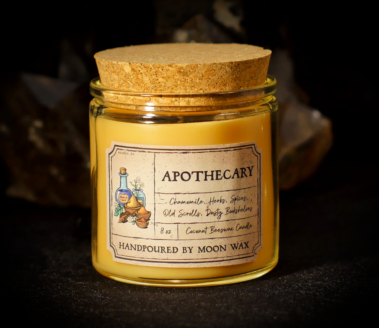 Apothecary Candle in a clear corked jar with creamy-yellow colored coconut beeswax and apothecary inspired label on a dark background. The label reads Chamomile, Herbs, Spices, Old Scrolls, Dusty Bookshelves, 8 ounces, and hand poured by Moon Wax.
