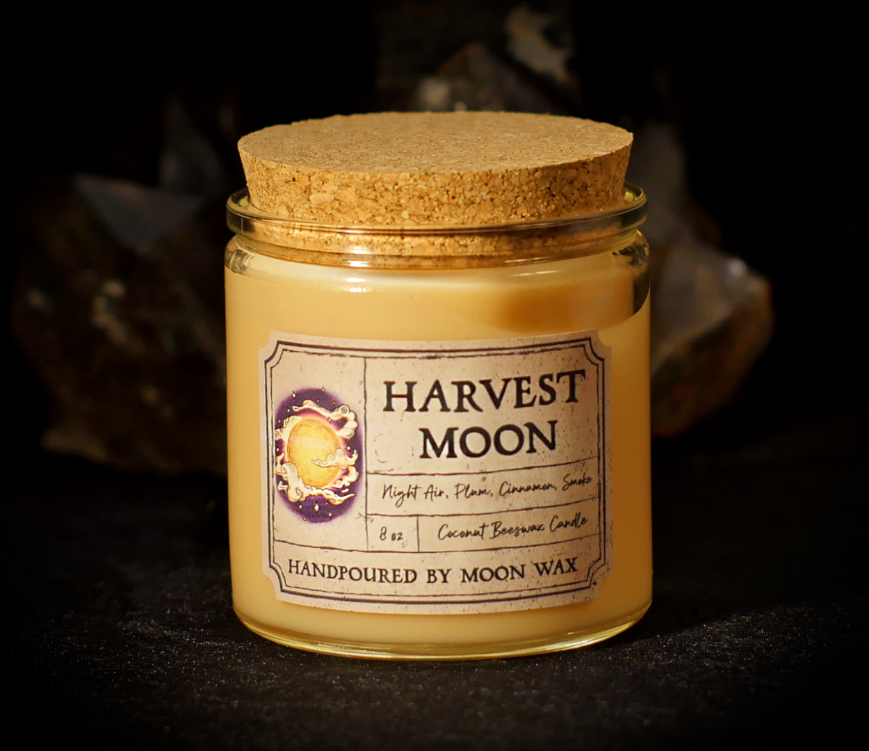 Harvest Moon Candle in a clear corked jar with cream colored coconut beeswax and apothecary inspired label on a dark background. The label reads Night Air, Plum, Cinnamon, Smoke, 8 ounces, and hand poured by Moon Wax.